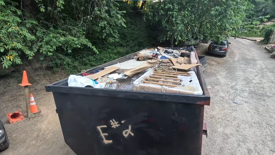 A dumpster being offloaded from a delivery truck