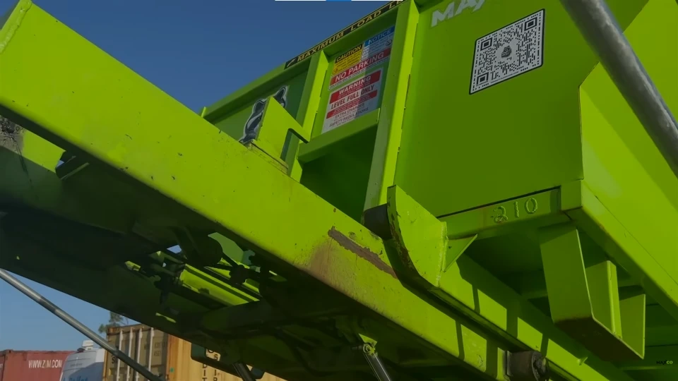 An empty roll-off dumpster with rollers for positioning on-site